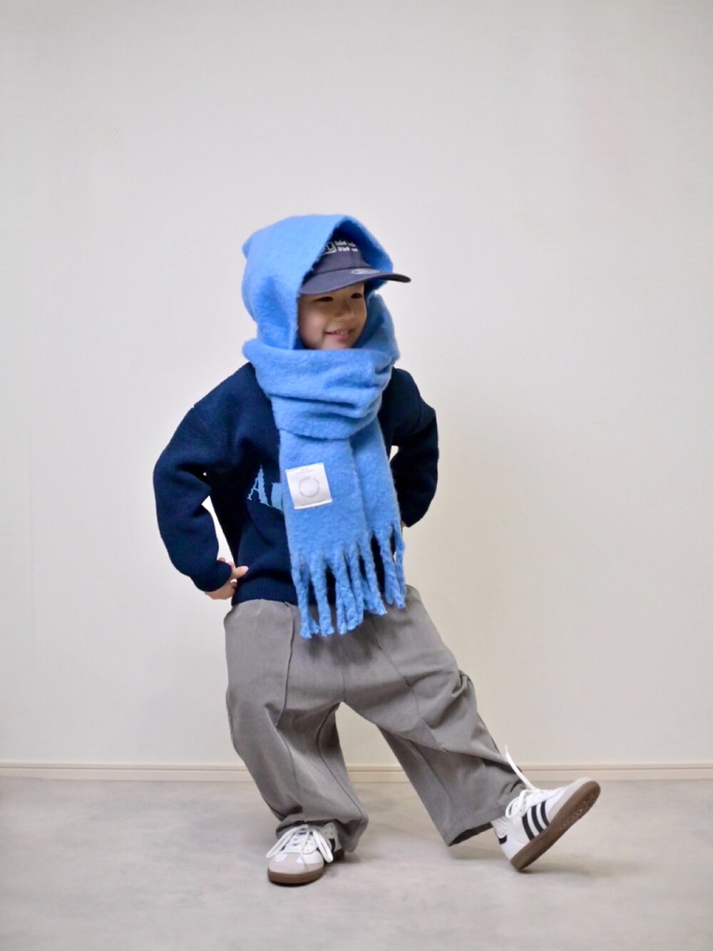 ブルー系のニット/セーター、グレー系のスラックス、ホワイト系のスニーカーを着用したキッズの冬コーディネートの3枚目の写真