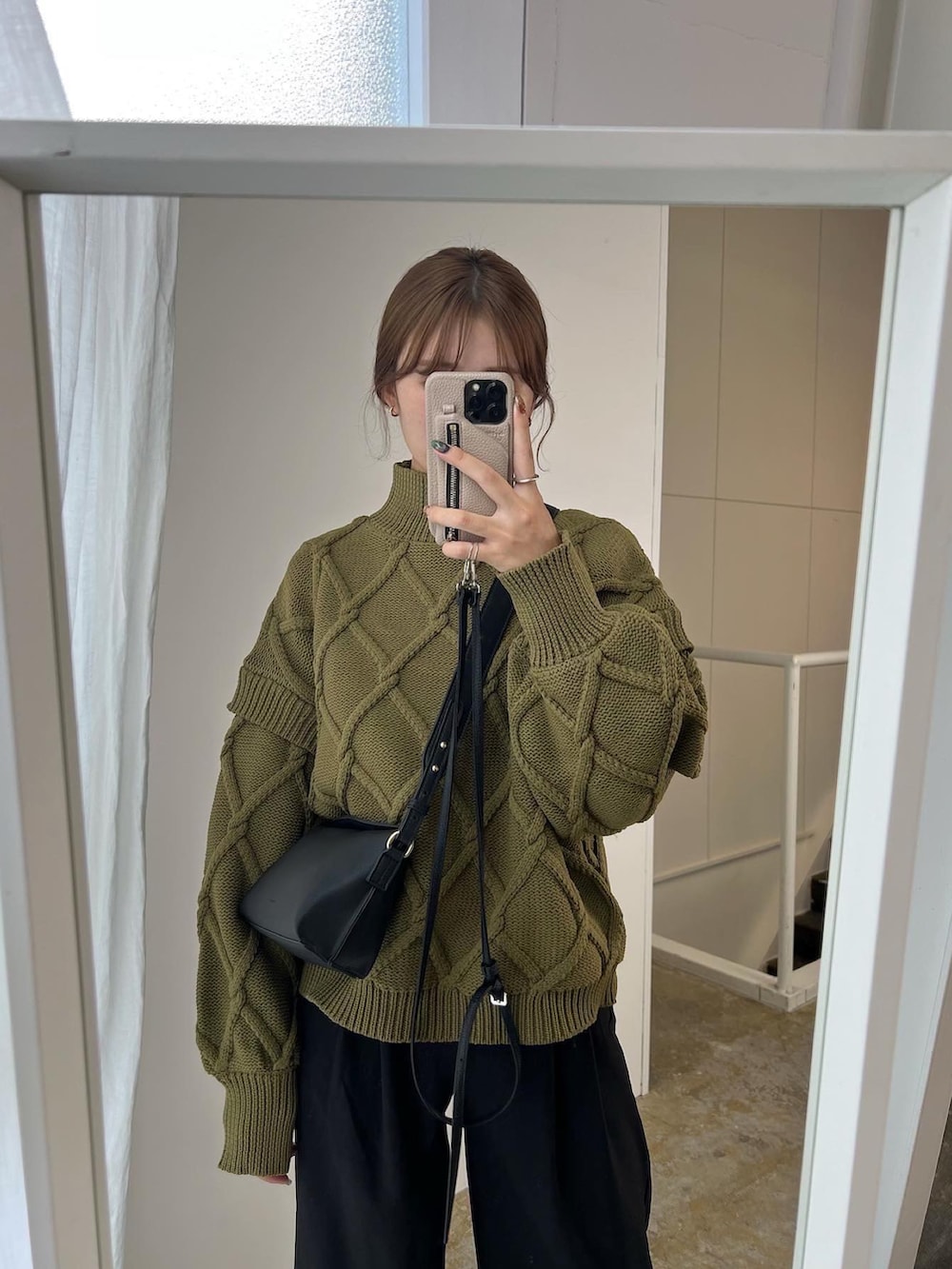 ブラック系のハンドバッグ、グリーン系のニット/セーターを着用したレディースの秋コーディネートの2枚目の写真