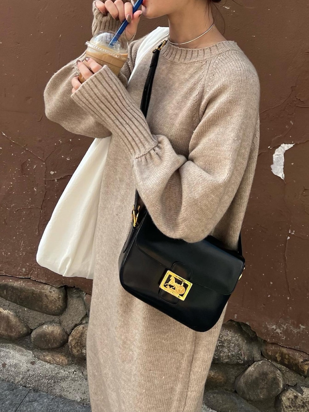 ベージュ系のワンピース、ホワイト系のトートバッグ、ブラック系のバッグを着用したレディースの秋コーディネートの2枚目の写真