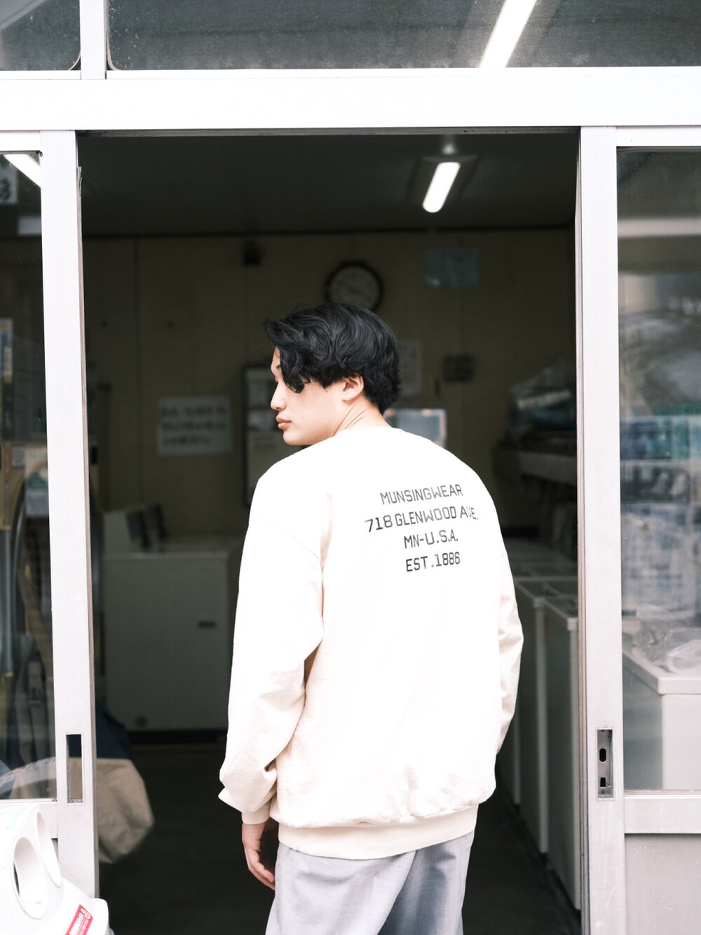 ホワイト系のスウェット、グレー系のスラックス、ブラック系のサンダルを着用したメンズの春コーディネートの3枚目の写真