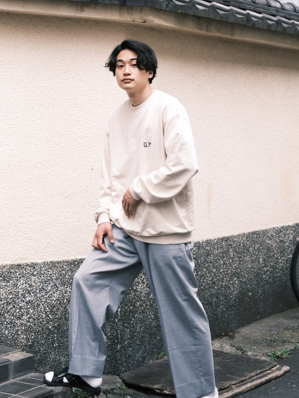 ホワイト系のスウェット、グレー系のスラックス、ブラック系のサンダルを着用したメンズの春コーディネートの2枚目の写真