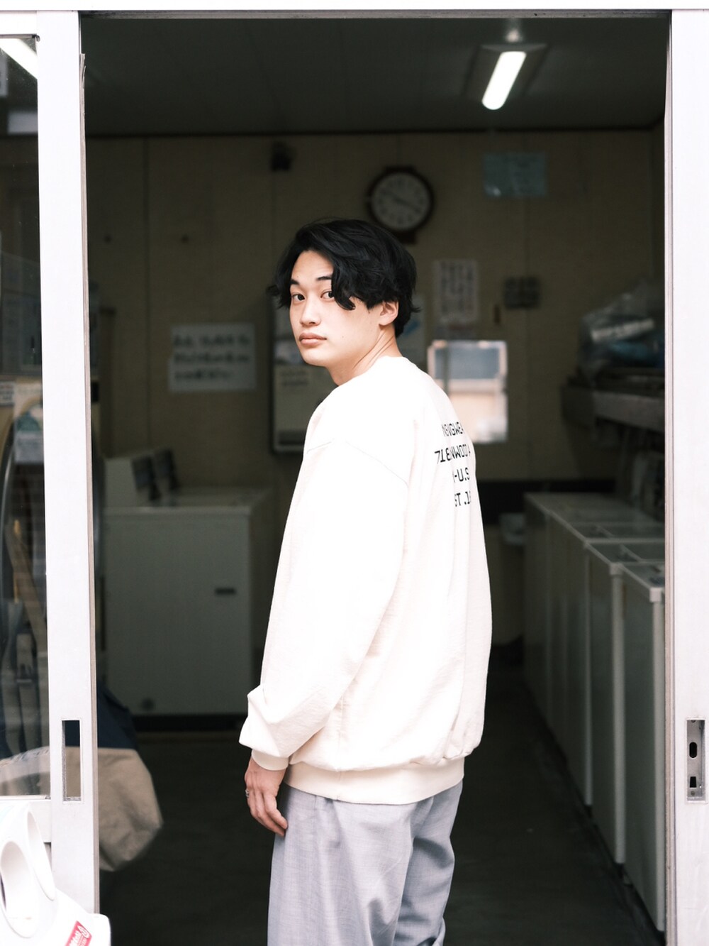 ホワイト系のスウェット、グレー系のスラックス、ブラック系のサンダルを着用したメンズの春コーディネートの4枚目の写真