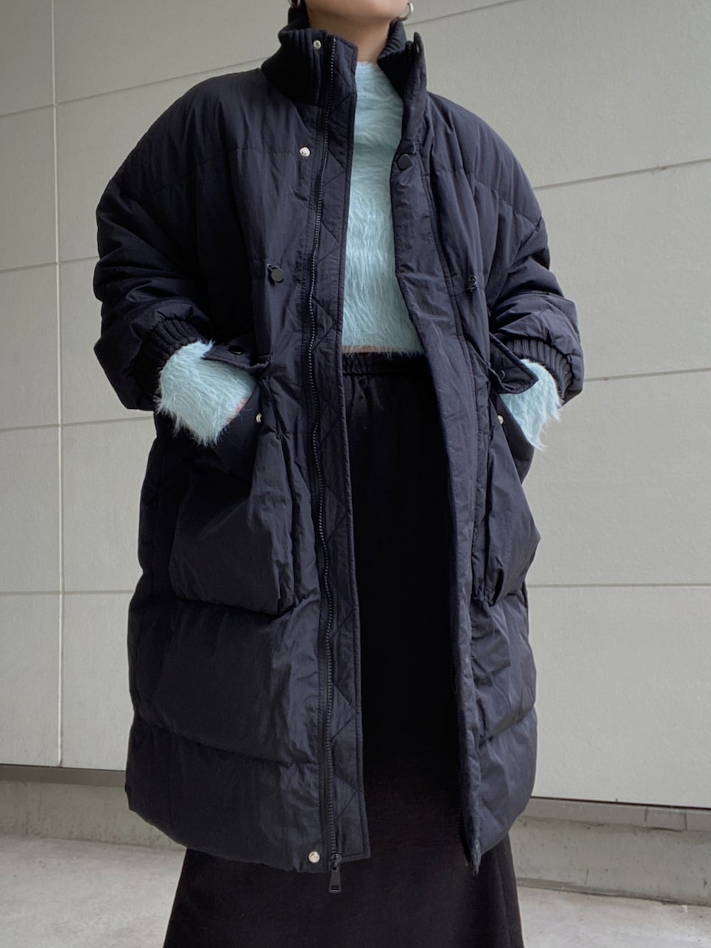 ブラック系のダウンジャケット/コート、ブルー系のニット/セーター、ブラック系のスカートを着用したレディースの冬コーディネートの2枚目の写真