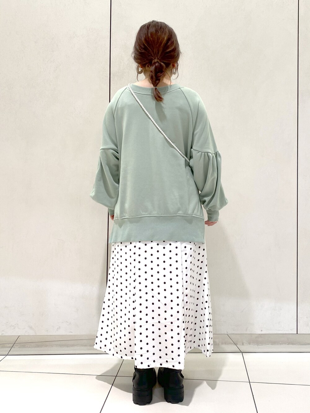 グリーン系のカーディガン/ボレロ、ホワイト系のスカート、ブラック系のブーツを着用したレディースの春コーディネートの3枚目の写真