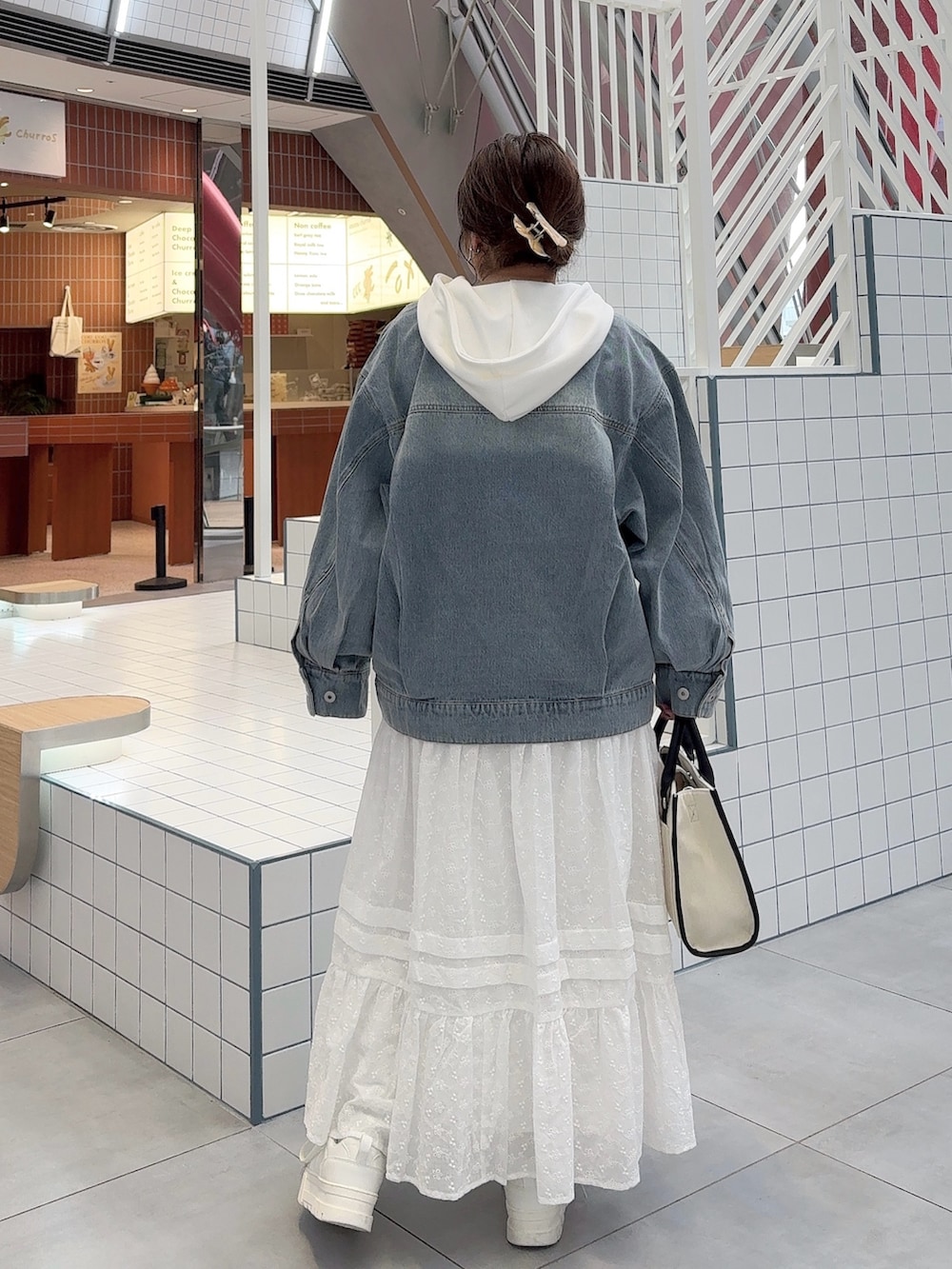 ブルー系のデニムジャケット、ホワイト系のスカート、ホワイト系のスニーカーを着用したレディースの冬コーディネートの3枚目の写真