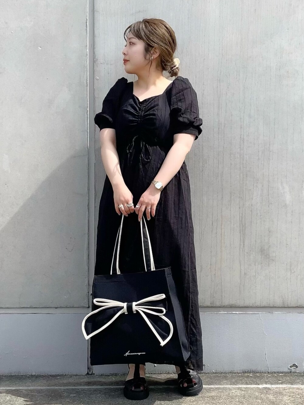 ブラック系のワンピース、ブラック系のトートバッグ、ブラック系のサンダルを着用したレディースの春コーディネートの2枚目の写真