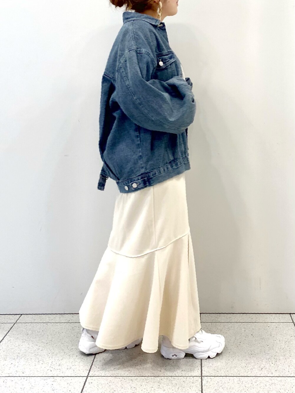 ホワイト系のスカート、ホワイト系のスニーカー、ブルー系のデニムジャケットを着用したレディースの春コーディネートの2枚目の写真