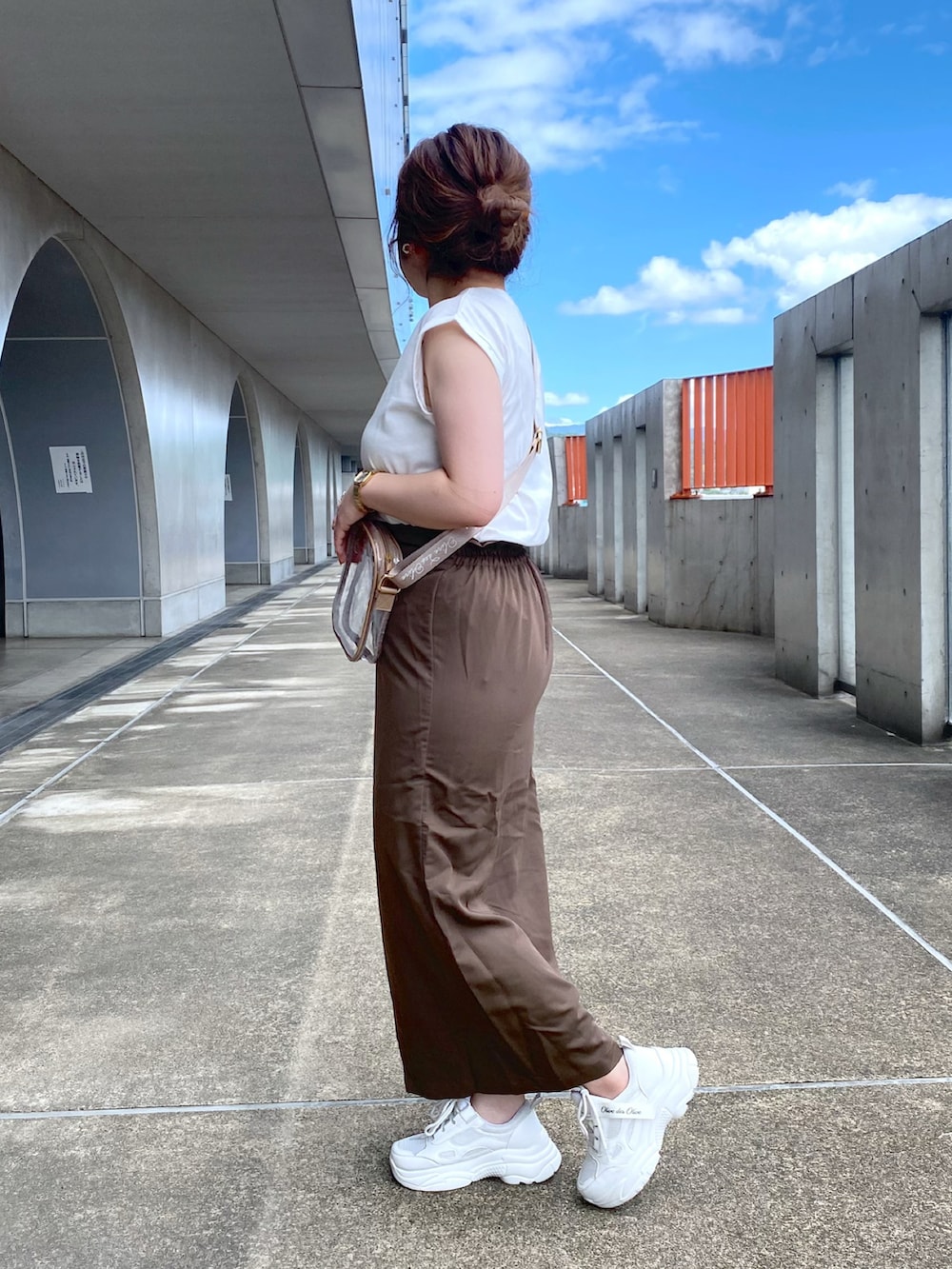ホワイト系のTシャツ/カットソー、ブラウン系のスカート、ホワイト系のスニーカーを着用したレディースの夏コーディネートの2枚目の写真