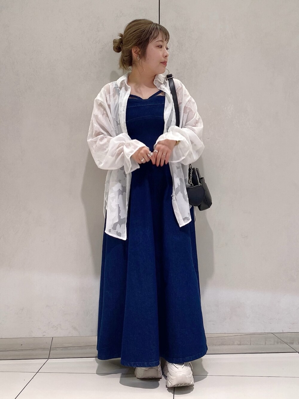 ブルー系のワンピース、ホワイト系のシャツ/ブラウス、ブラック系のショルダーバッグを着用したレディースの春コーディネートの2枚目の写真