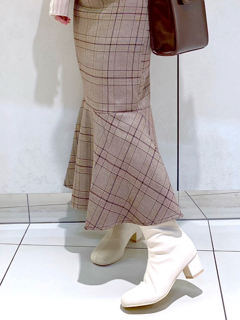 ベージュ系のニット/セーター、ブラウン系のスカート、ホワイト系のブーツを着用したレディースの秋コーディネートの2枚目の写真