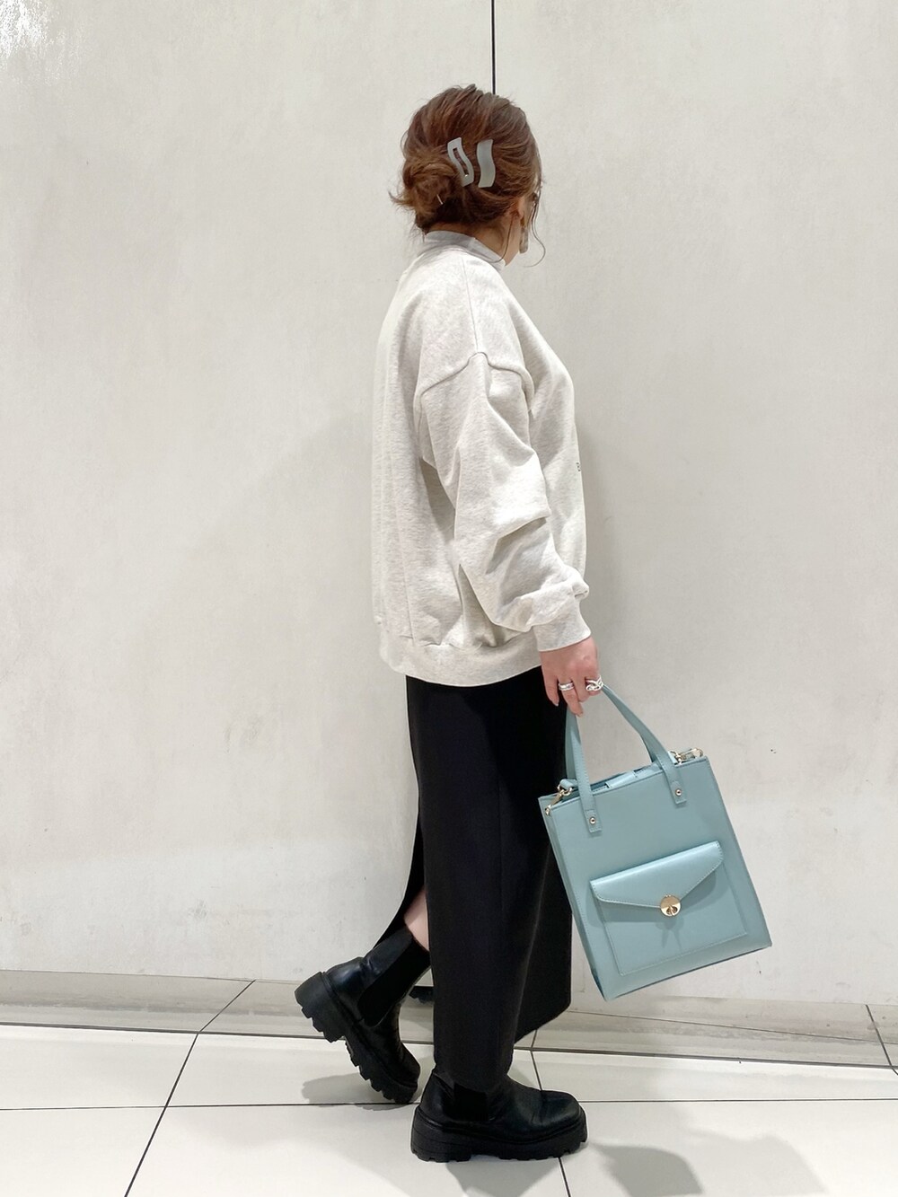 グレー系のスウェット、ブラック系のスカート、ブラック系のブーツを着用したレディースの春コーディネートの2枚目の写真