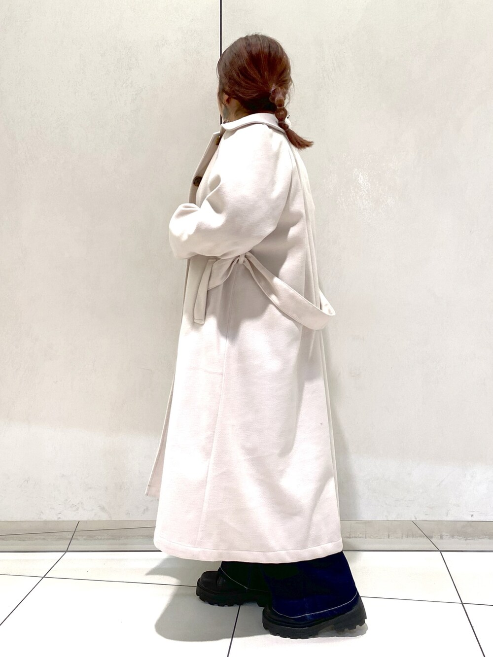 ホワイト系のステンカラーコート、ブラック系のシャツ/ブラウス、ブラック系のブーツを着用したレディースの冬コーディネートの2枚目の写真