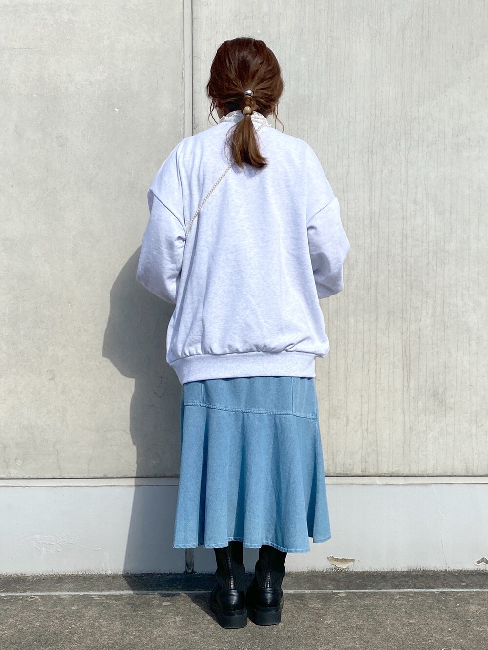 ベージュ系のスウェット、ブルー系のスカート、ブラック系のブーツを着用したレディースの冬コーディネートの3枚目の写真