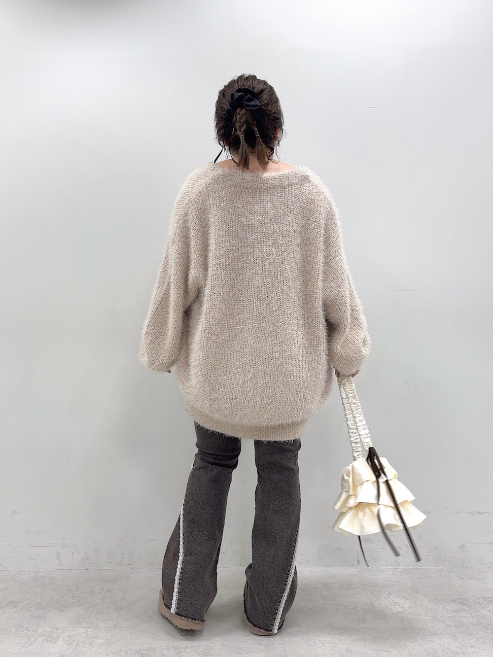 ベージュ系のカーディガン/ボレロ、ベージュ系のワンピース、ブラック系のデニムパンツを着用したレディースの秋コーディネートの3枚目の写真