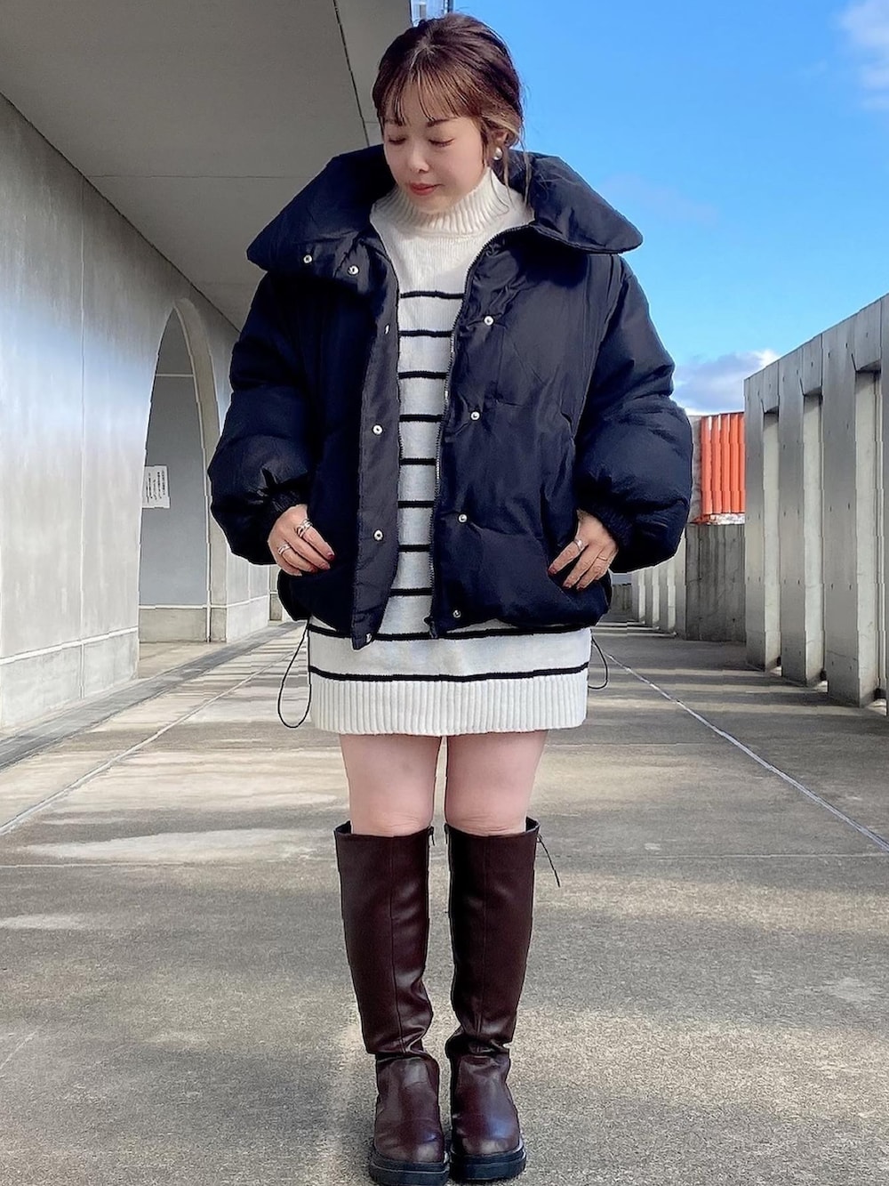 ブラック系のダウンジャケット/コート、ホワイト系のニット/セーター、ブラウン系のブーツを着用したレディースの冬コーディネートの2枚目の写真