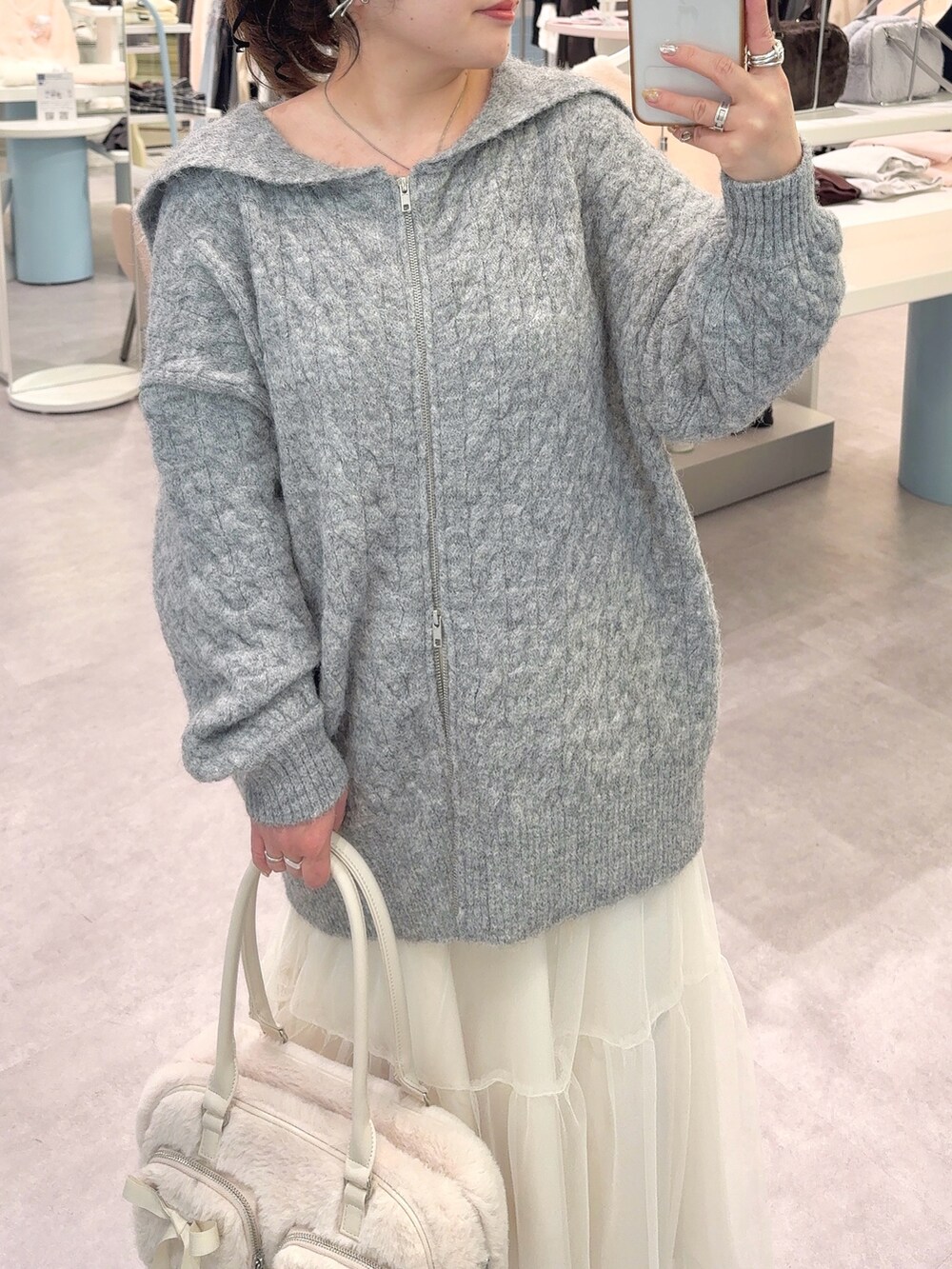 グレー系のワンピース、ホワイト系のスカート、ホワイト系のショルダーバッグを着用したレディースの冬コーディネートの2枚目の写真