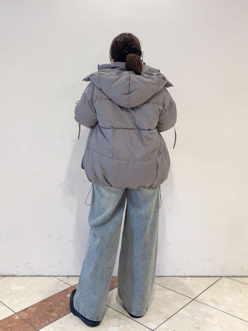 グレー系のダウンジャケット/コート、ホワイト系のニット/セーター、ブルー系のデニムパンツを着用したレディースの秋コーディネートの4枚目の写真