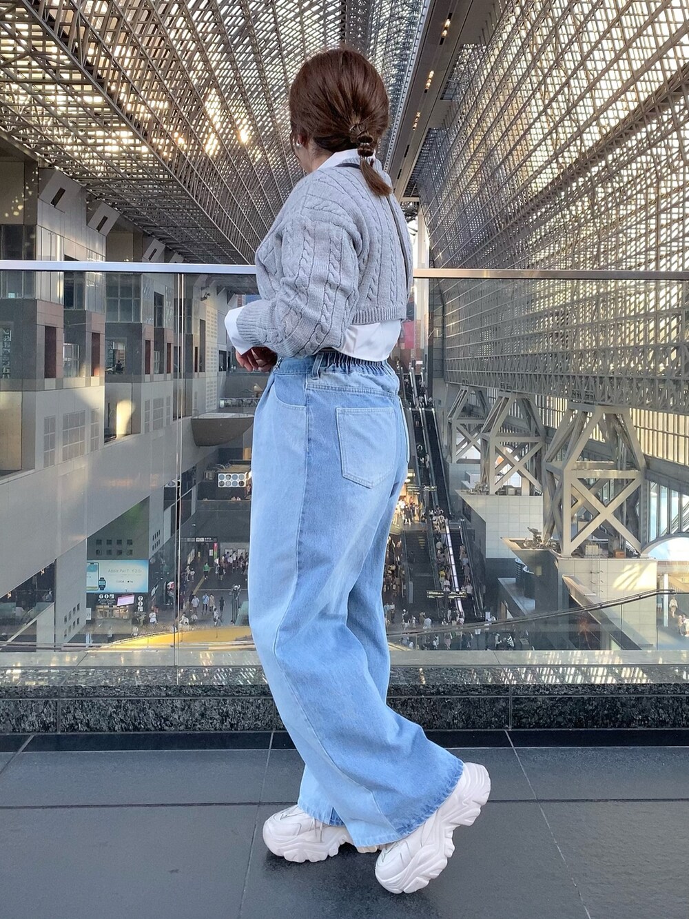 グレー系のニット/セーター、ブルー系のデニムパンツ、ブラック系のショルダーバッグを着用したレディースの夏コーディネートの3枚目の写真