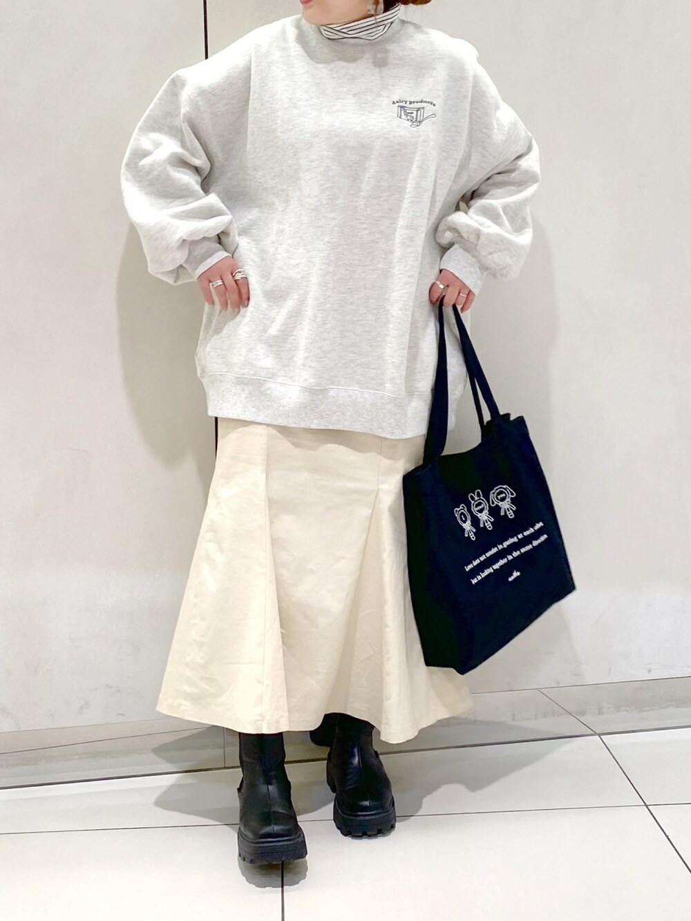 グレー系のスウェット、ホワイト系のスカート、ブラック系のブーツを着用したレディースの冬コーディネートの3枚目の写真