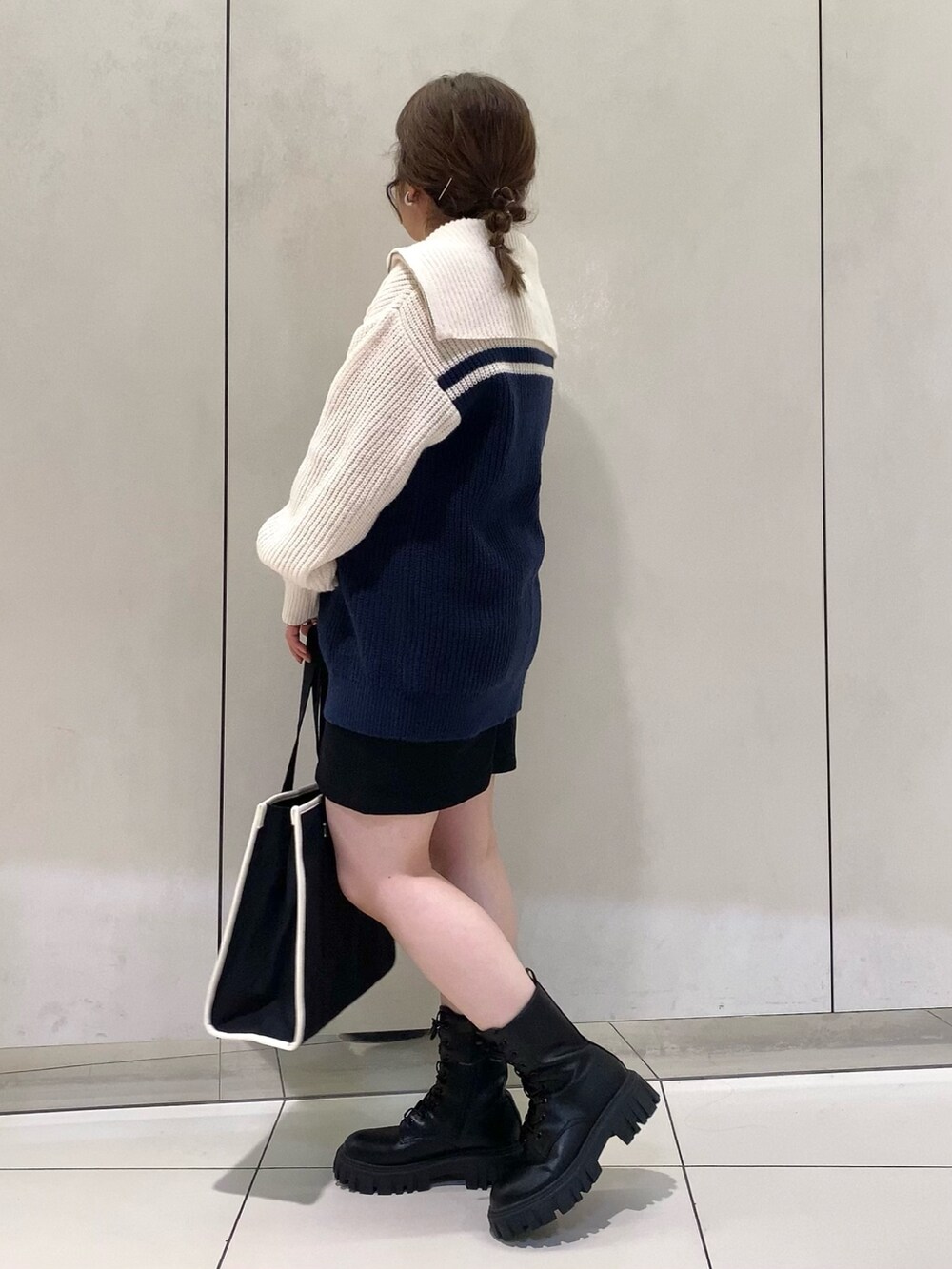 ブルー系のニット/セーター、ブラック系のスカート、ブラック系のトートバッグを着用したレディースの夏コーディネートの3枚目の写真
