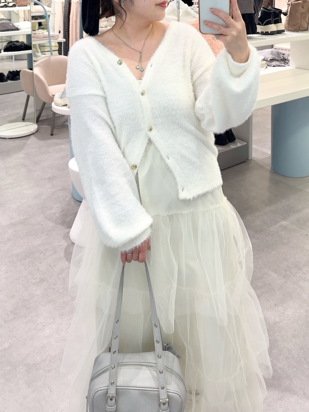 ホワイト系のワンピース、ブルー系のショルダーバッグ、ホワイト系のスニーカーを着用したレディースの冬コーディネートの2枚目の写真