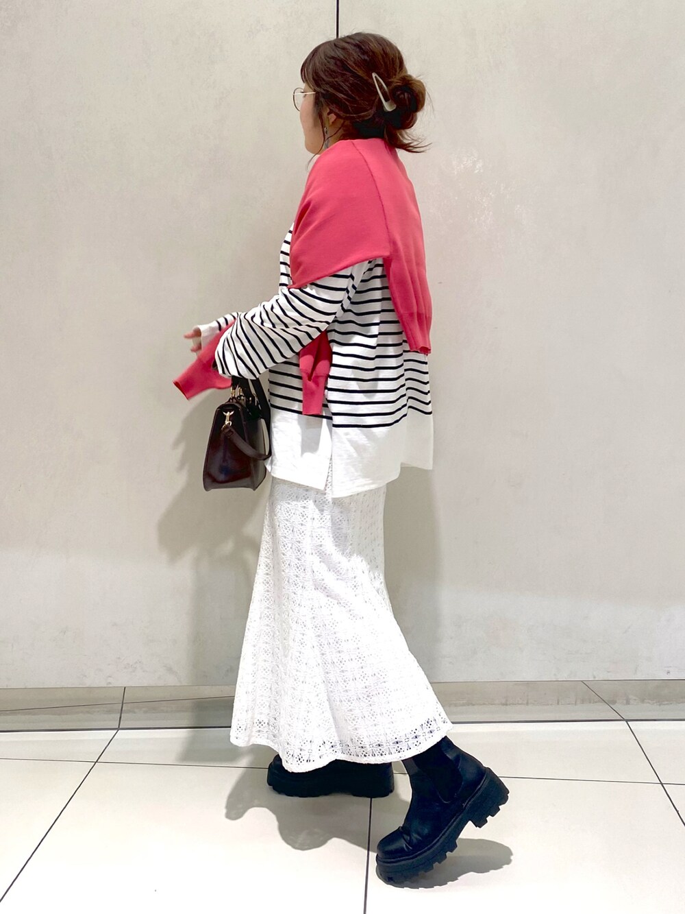 ピンク系のカーディガン/ボレロ、ブラック系のTシャツ/カットソー、ホワイト系のスカートを着用したレディースの冬コーディネートの2枚目の写真