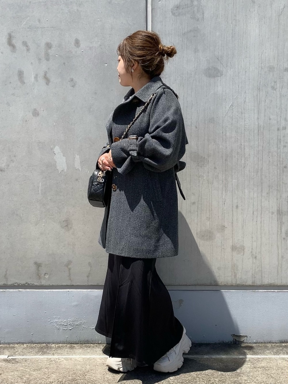 グレー系のステンカラーコート、ブラック系のショルダーバッグ、ブラック系のスカートを着用したレディースの夏コーディネートの3枚目の写真