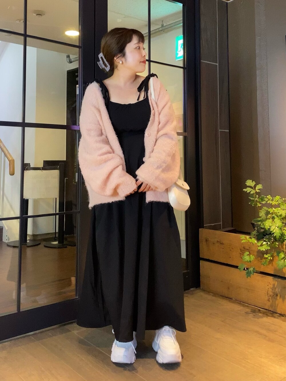 ピンク系のカーディガン/ボレロ、ブラック系のワンピース、ホワイト系のスニーカーを着用したレディースの秋コーディネートの2枚目の写真