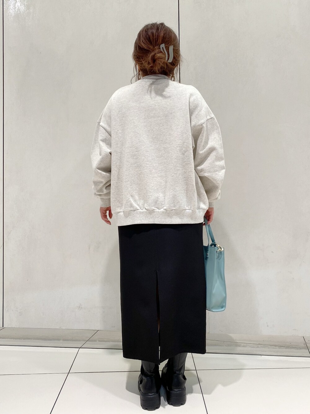 グレー系のスウェット、ブラック系のスカート、ブラック系のブーツを着用したレディースの春コーディネートの3枚目の写真