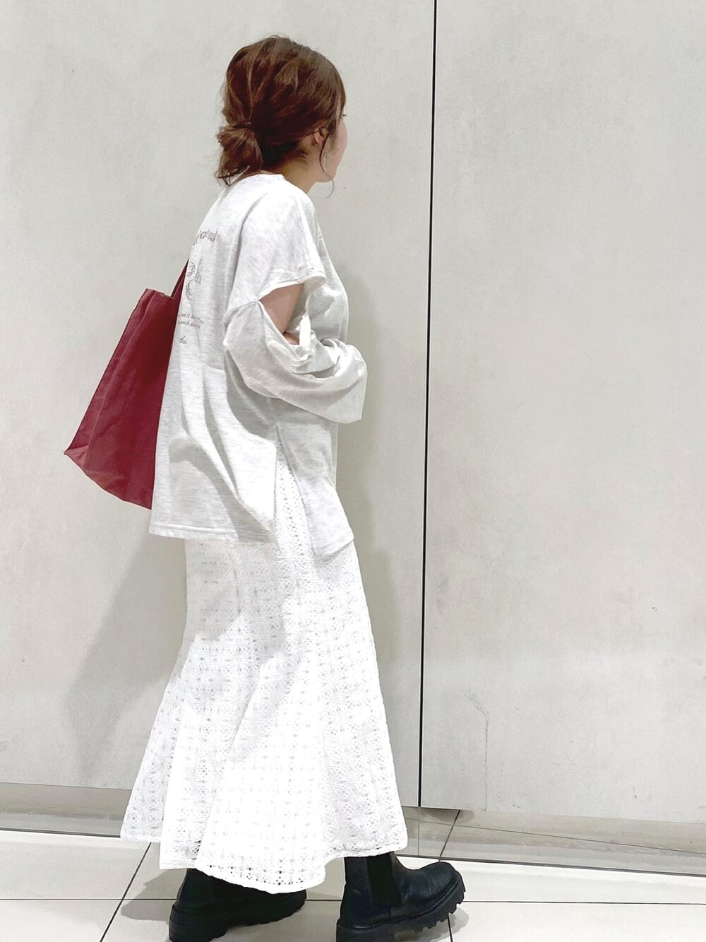 グレー系のTシャツ/カットソー、ホワイト系のスカート、ブラック系のブーツを着用したレディースの冬コーディネートの2枚目の写真