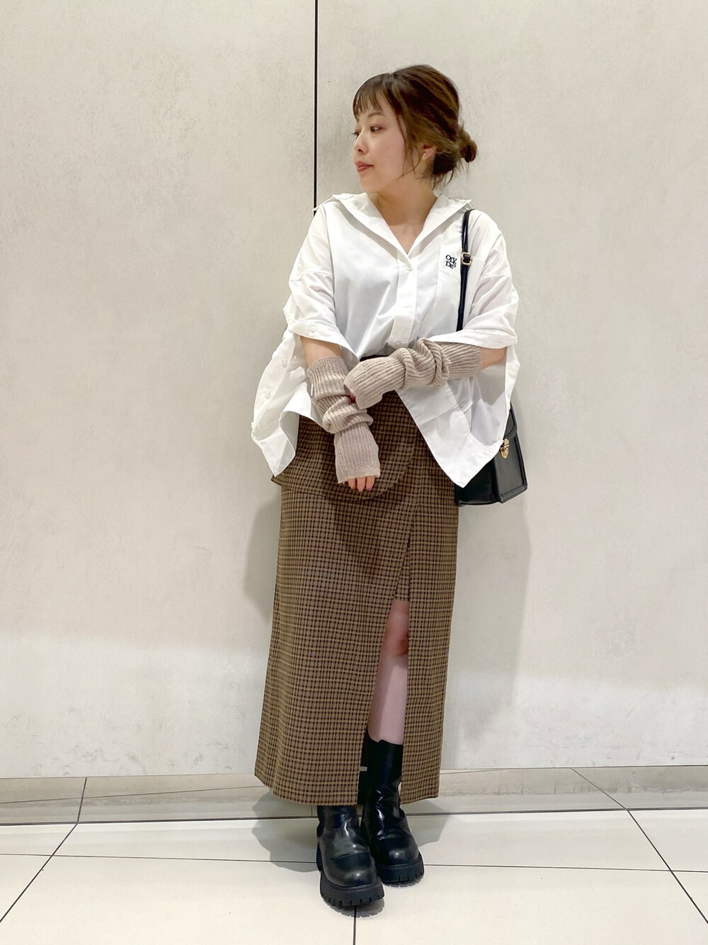 ホワイト系のシャツ/ブラウス、ブラウン系のスカート、ブラック系のブーツを着用したレディースの秋コーディネートの2枚目の写真