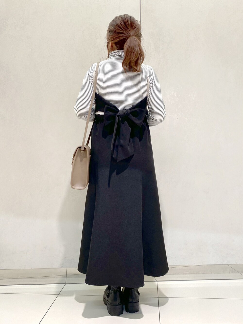 ブラック系のジャンパースカート、ベージュ系のショルダーバッグ、ブラック系のTシャツ/カットソーを着用したレディースの春コーディネートの2枚目の写真