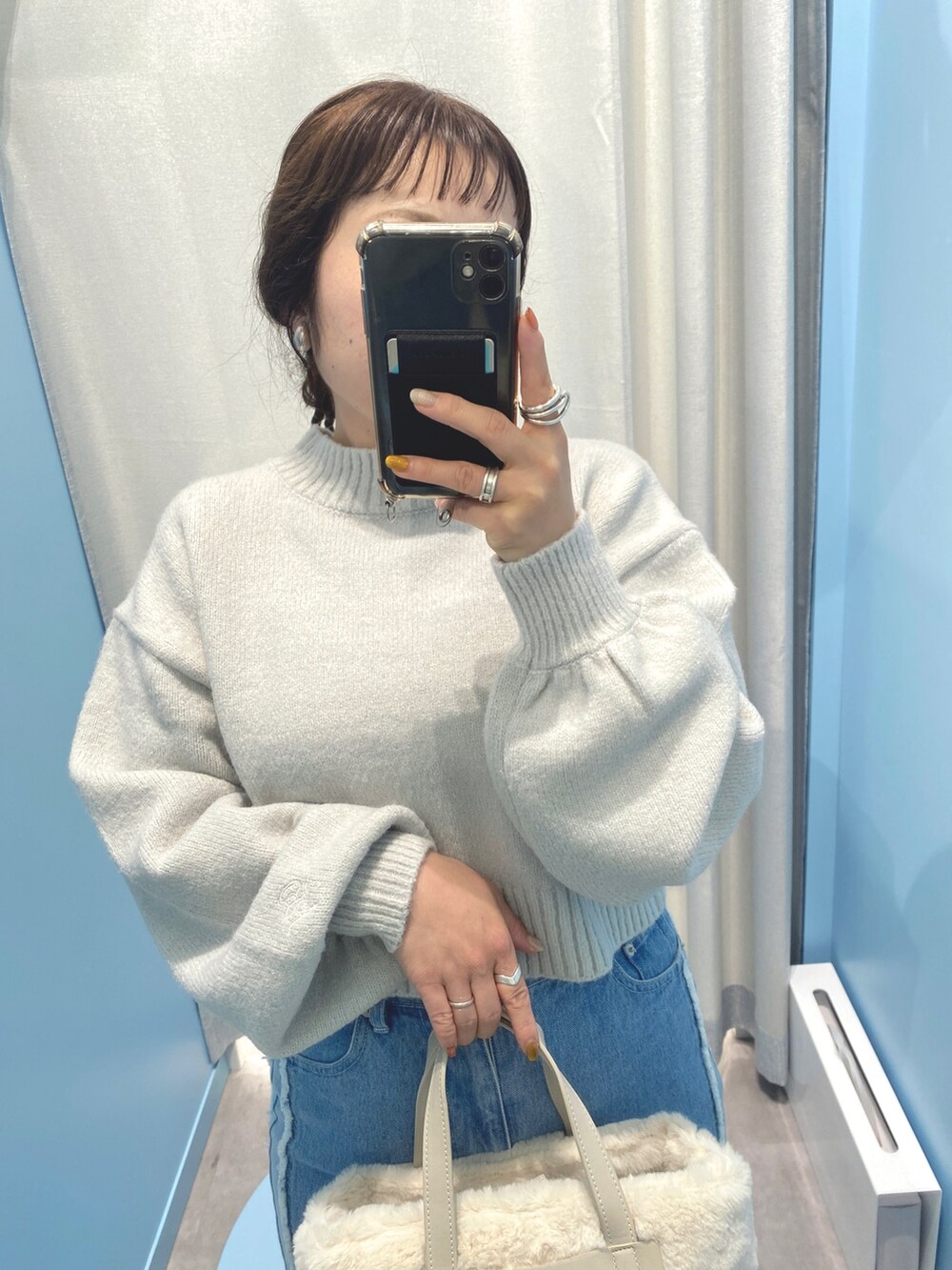 グレー系のニット/セーター、ブルー系のデニムパンツ、ホワイト系のショルダーバッグを着用したレディースの秋コーディネートの2枚目の写真