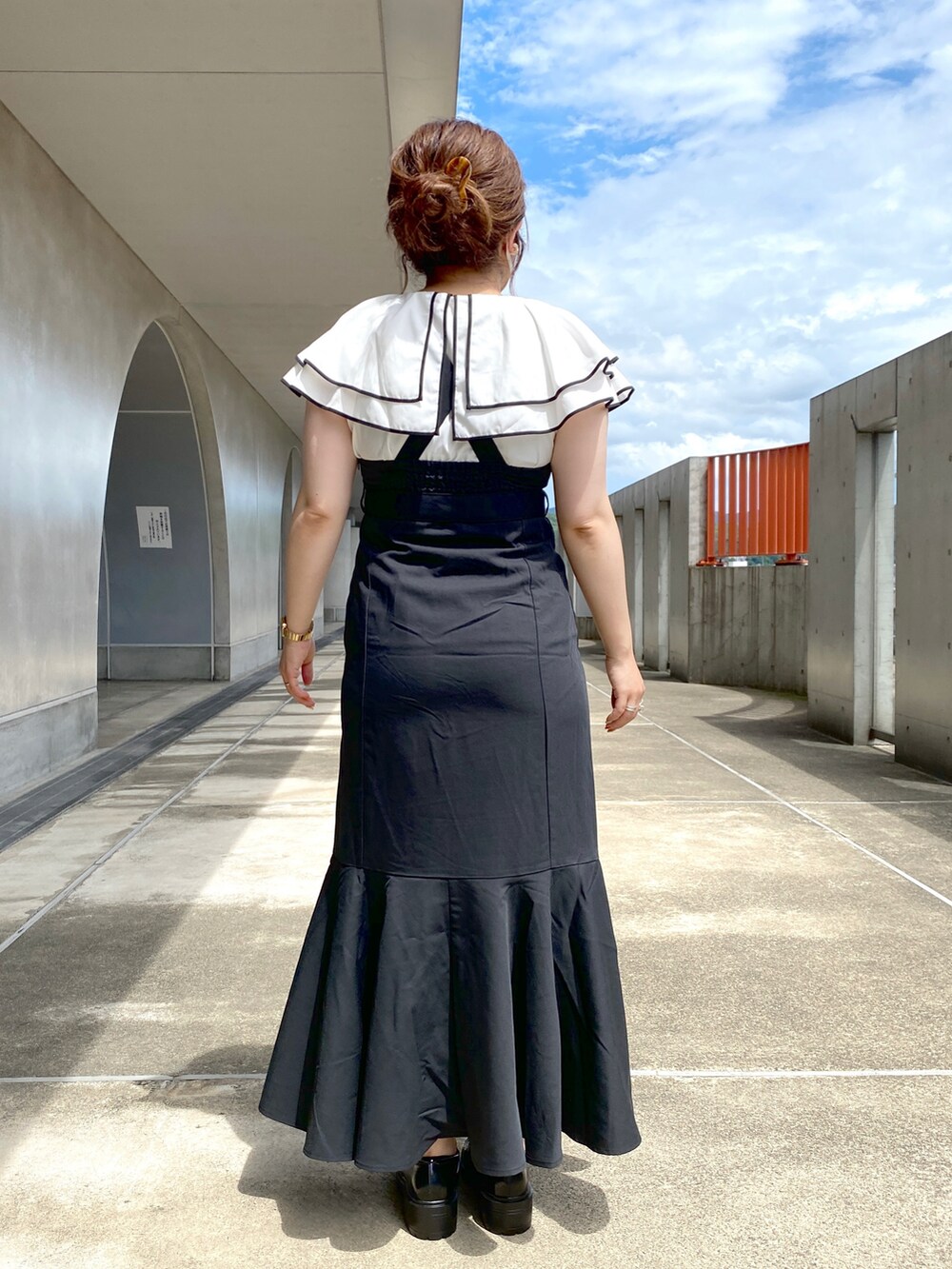 ブラック系のジャンパースカート、ホワイト系のシャツ/ブラウス、ブラック系のローファーを着用したレディースの夏コーディネートの3枚目の写真
