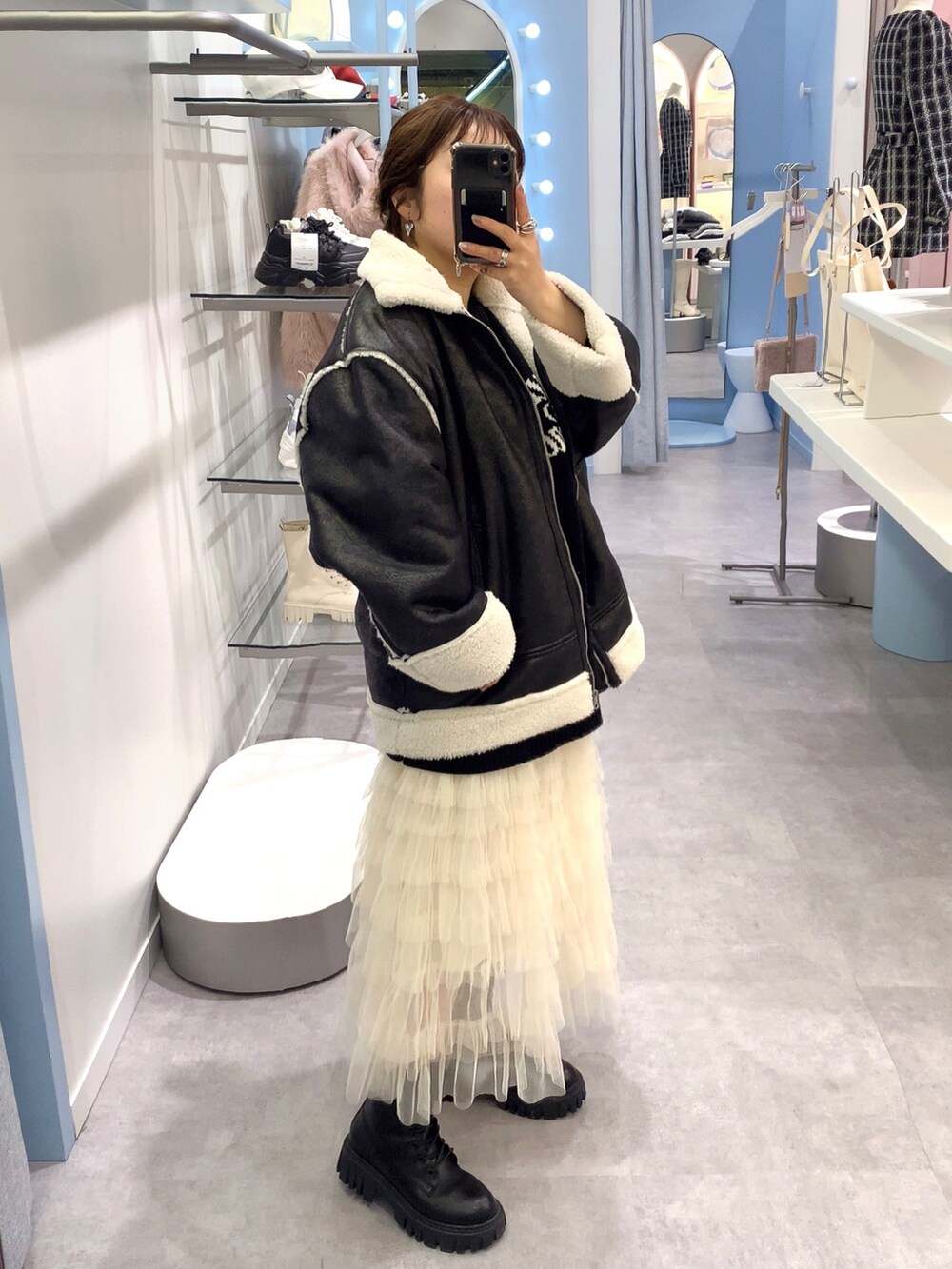 ブラック系のムートンコート、ブラック系のニット/セーター、ホワイト系のスカートを着用したレディースの秋コーディネートの3枚目の写真