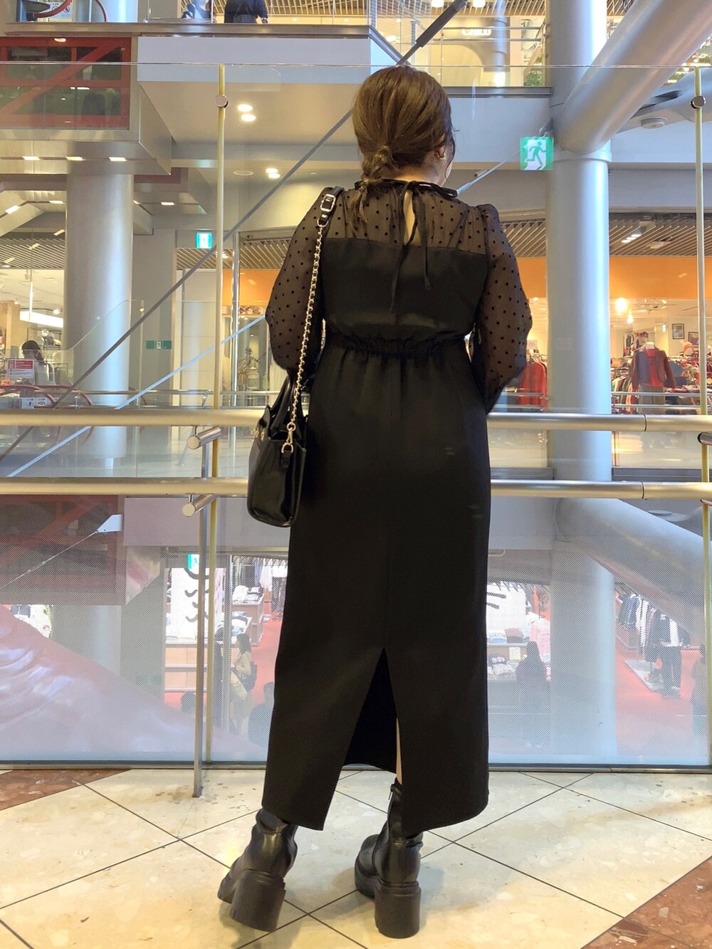 ブラック系のドレス、ブラック系のショルダーバッグ、ブラック系のブーツを着用したレディースの秋コーディネートの4枚目の写真