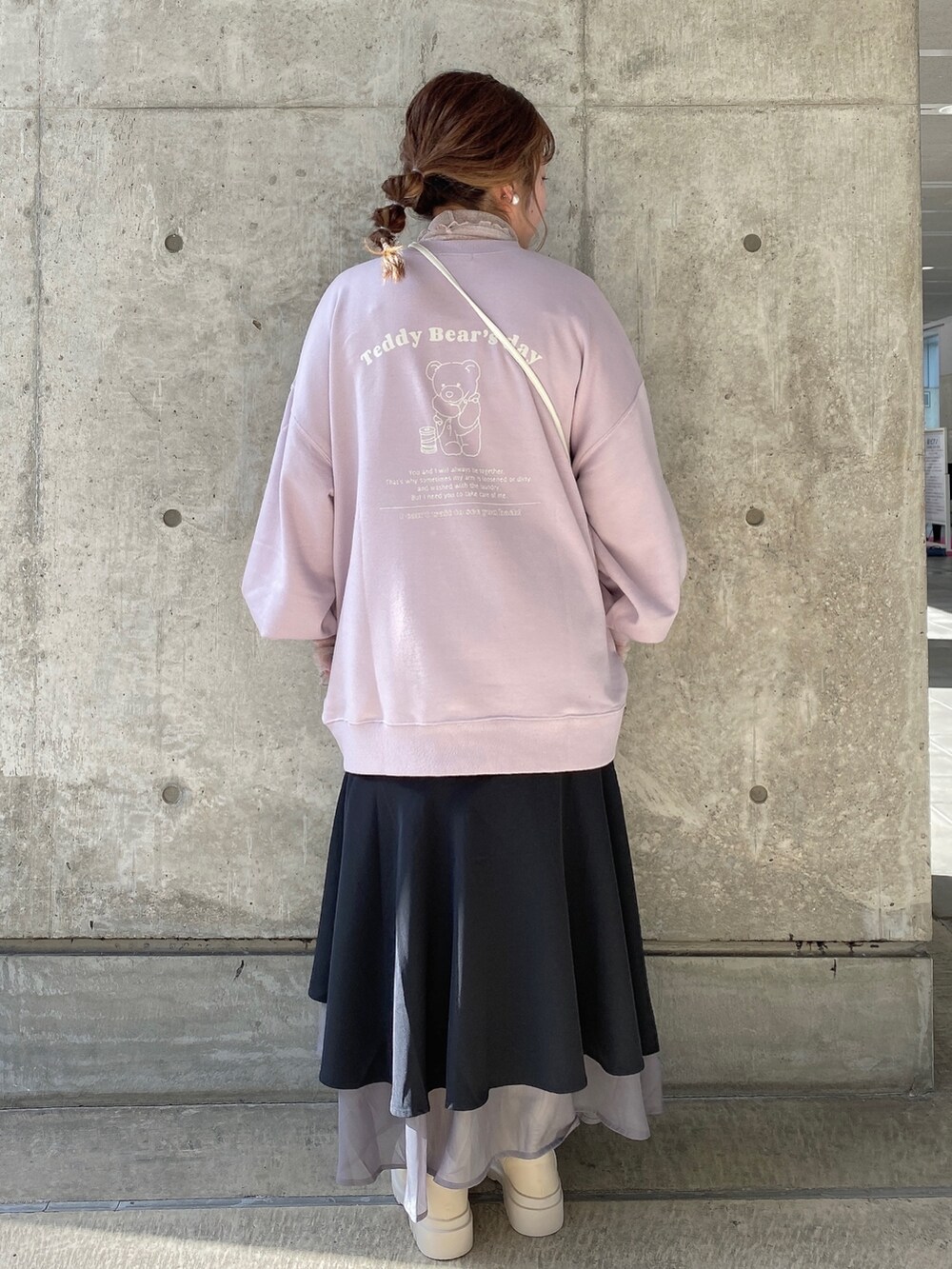 ピンク系のスウェット、ブラック系のスカート、ホワイト系のブーツを着用したレディースの冬コーディネートの3枚目の写真