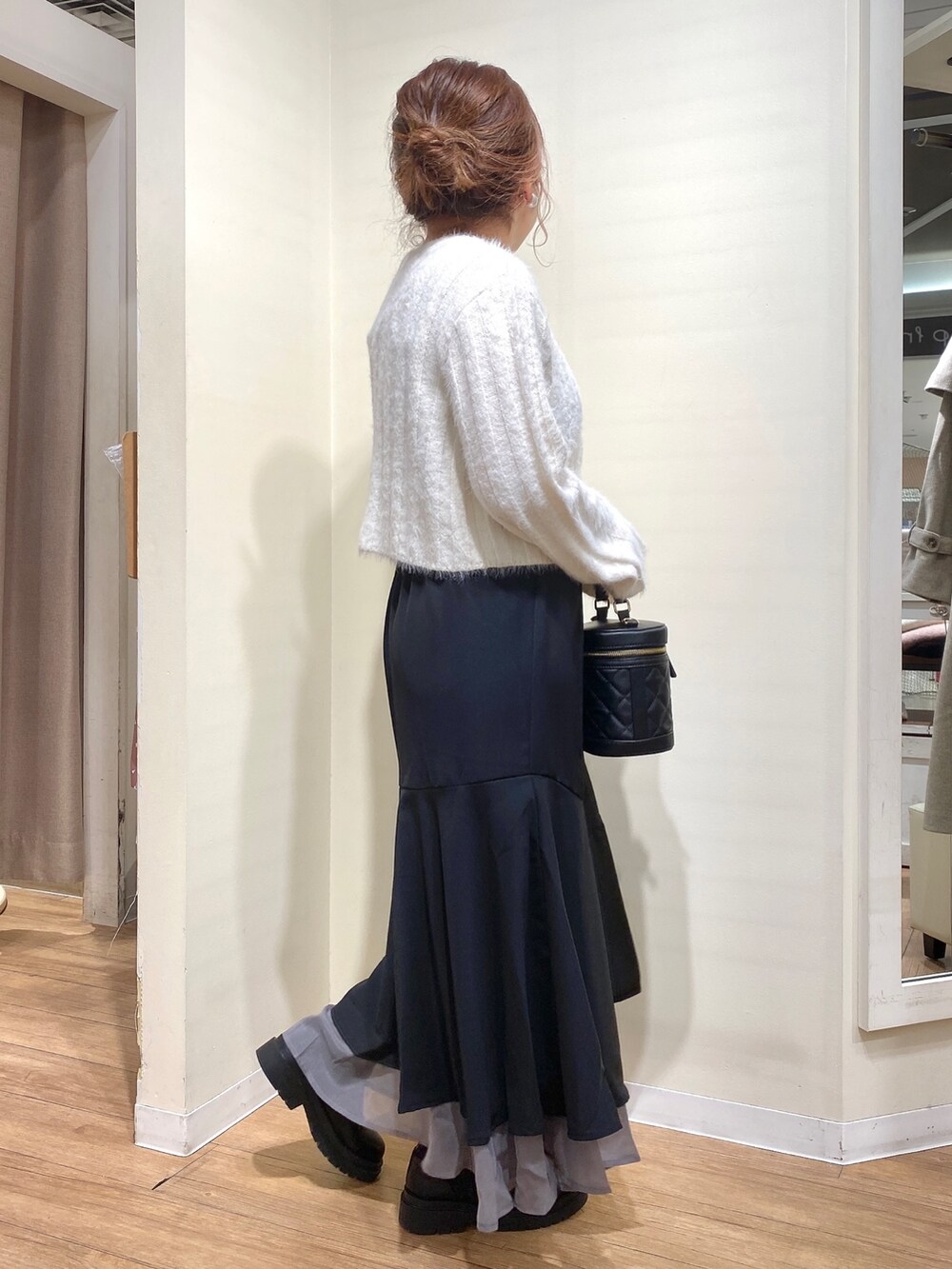 ブラック系のニット/セーター、ブラック系のショルダーバッグ、ブラック系のスカートを着用したレディースの冬コーディネートの2枚目の写真