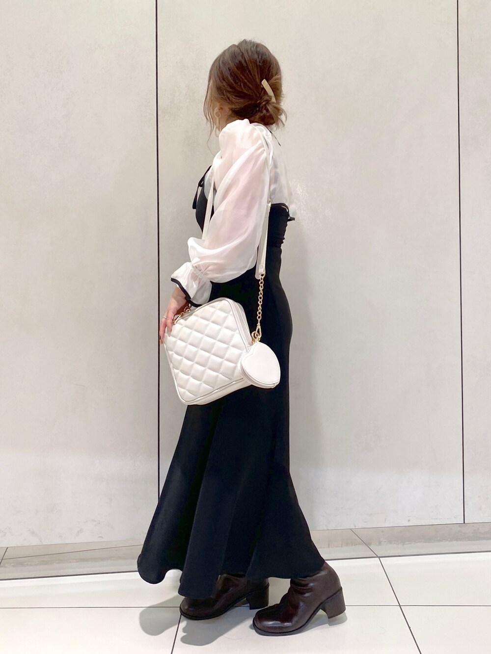 ブラック系のワンピース、ホワイト系のショルダーバッグ、ブラウン系のブーツを着用したレディースの秋コーディネートの2枚目の写真