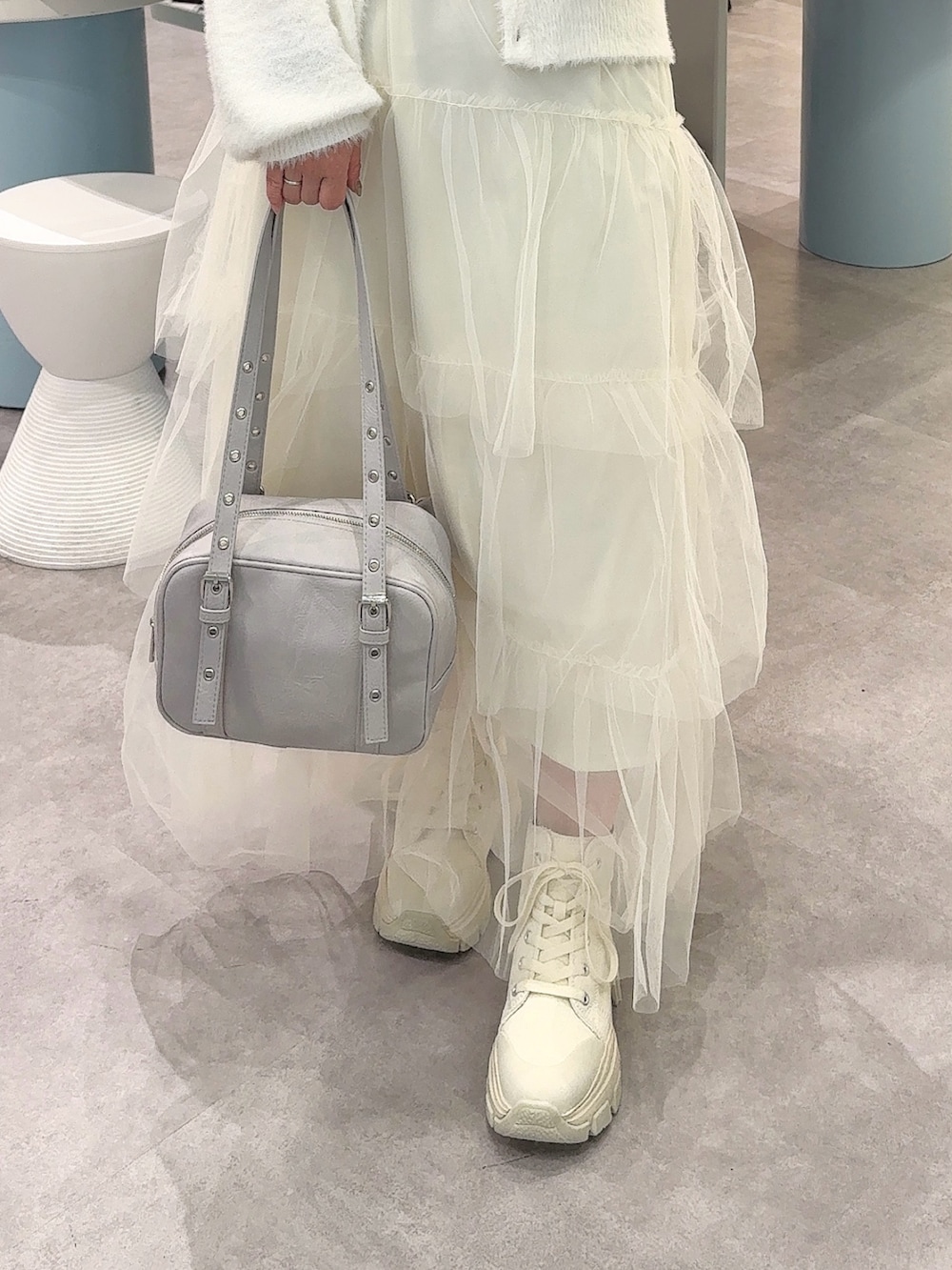 ホワイト系のワンピース、ブルー系のショルダーバッグ、ホワイト系のスニーカーを着用したレディースの冬コーディネートの3枚目の写真