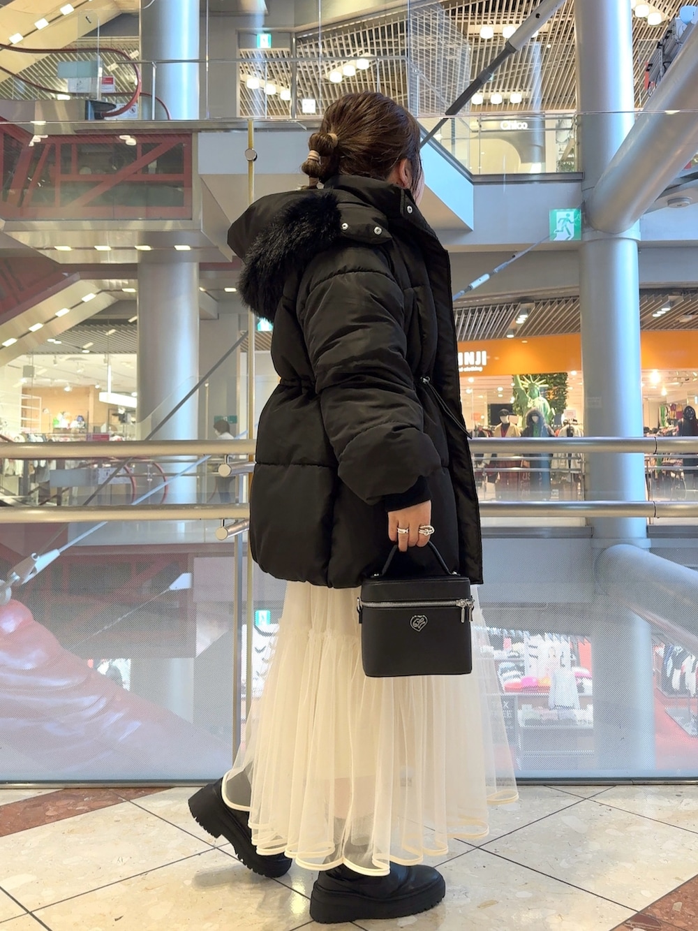 ブラック系のダウンジャケット/コート、ホワイト系のニット/セーター、ホワイト系のスカートを着用したレディースの冬コーディネートの2枚目の写真