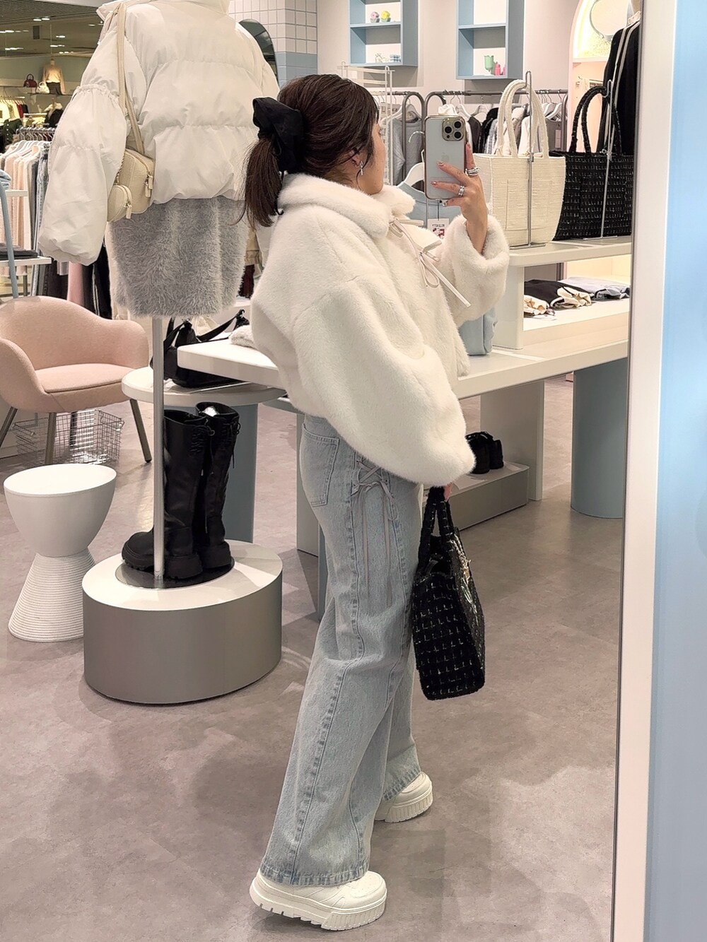 ホワイト系のブルゾン、ブルー系のその他パンツ、ブラック系のトートバッグを着用したレディースの秋コーディネートの3枚目の写真