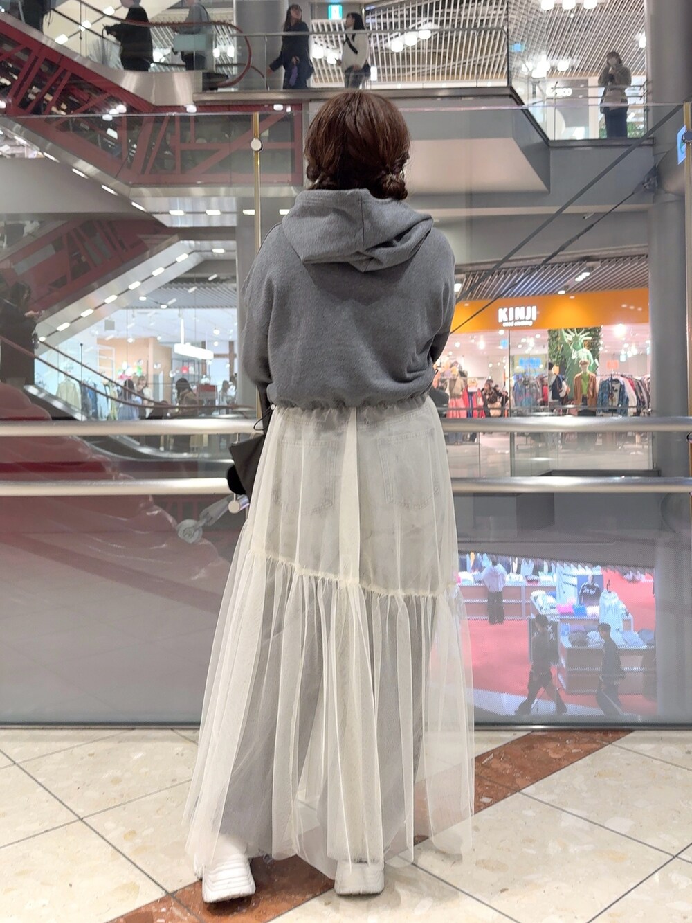 グレー系のパーカー、ホワイト系のスカート、ブラック系のトートバッグを着用したレディースの冬コーディネートの3枚目の写真