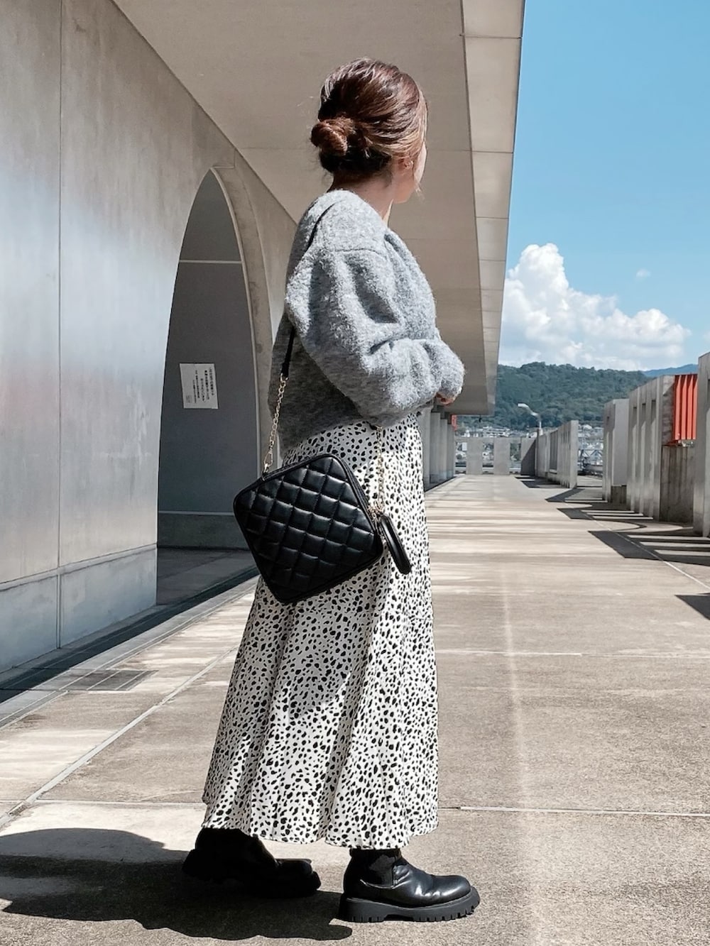 ホワイト系のスカート、ブラック系のブーツ、ブラック系のショルダーバッグを着用したレディースの秋コーディネートの2枚目の写真