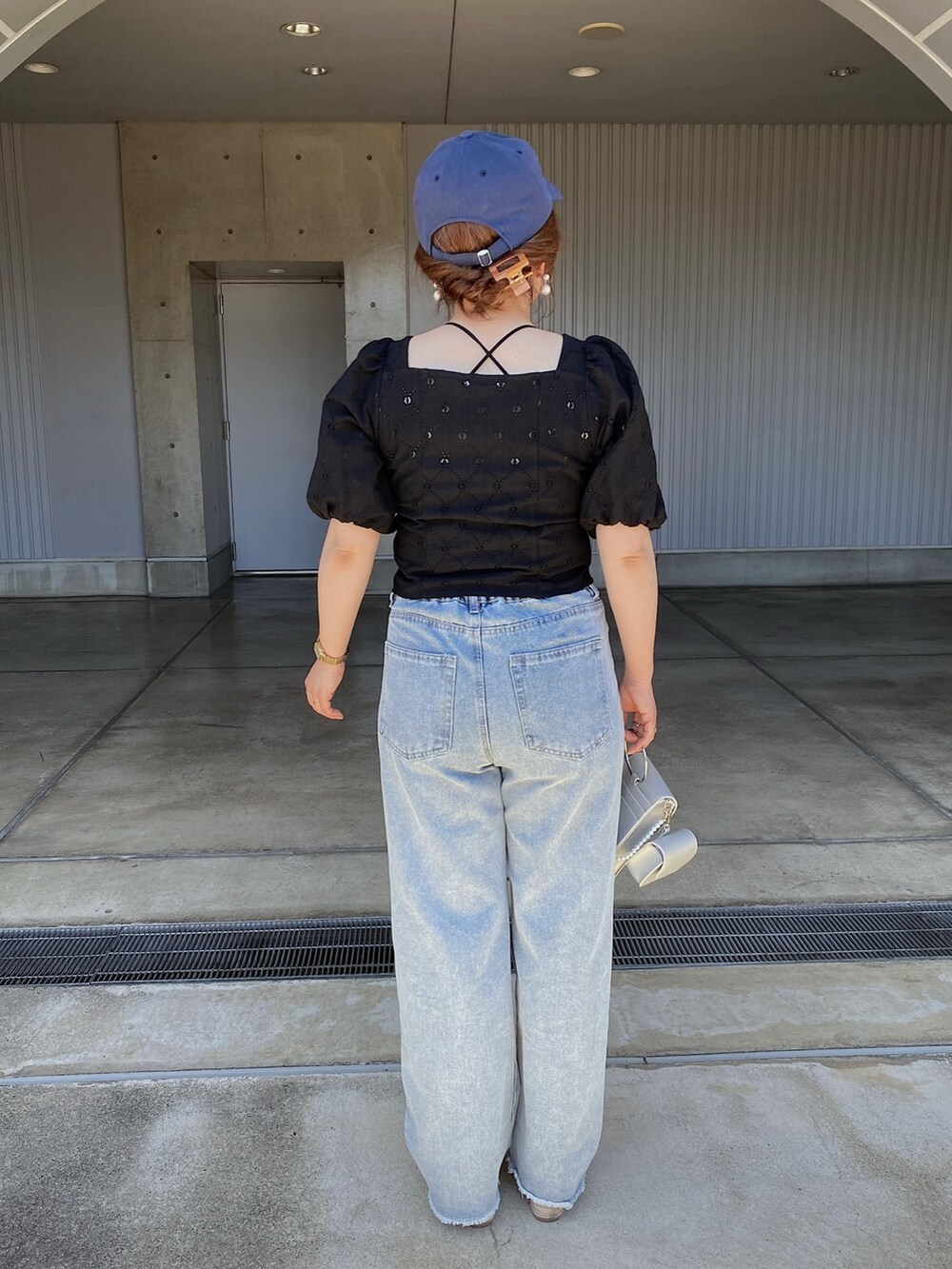 ブルー系のデニムパンツ、ホワイト系のサンダル、ブラック系のシャツ/ブラウスを着用したレディースの夏コーディネートの3枚目の写真