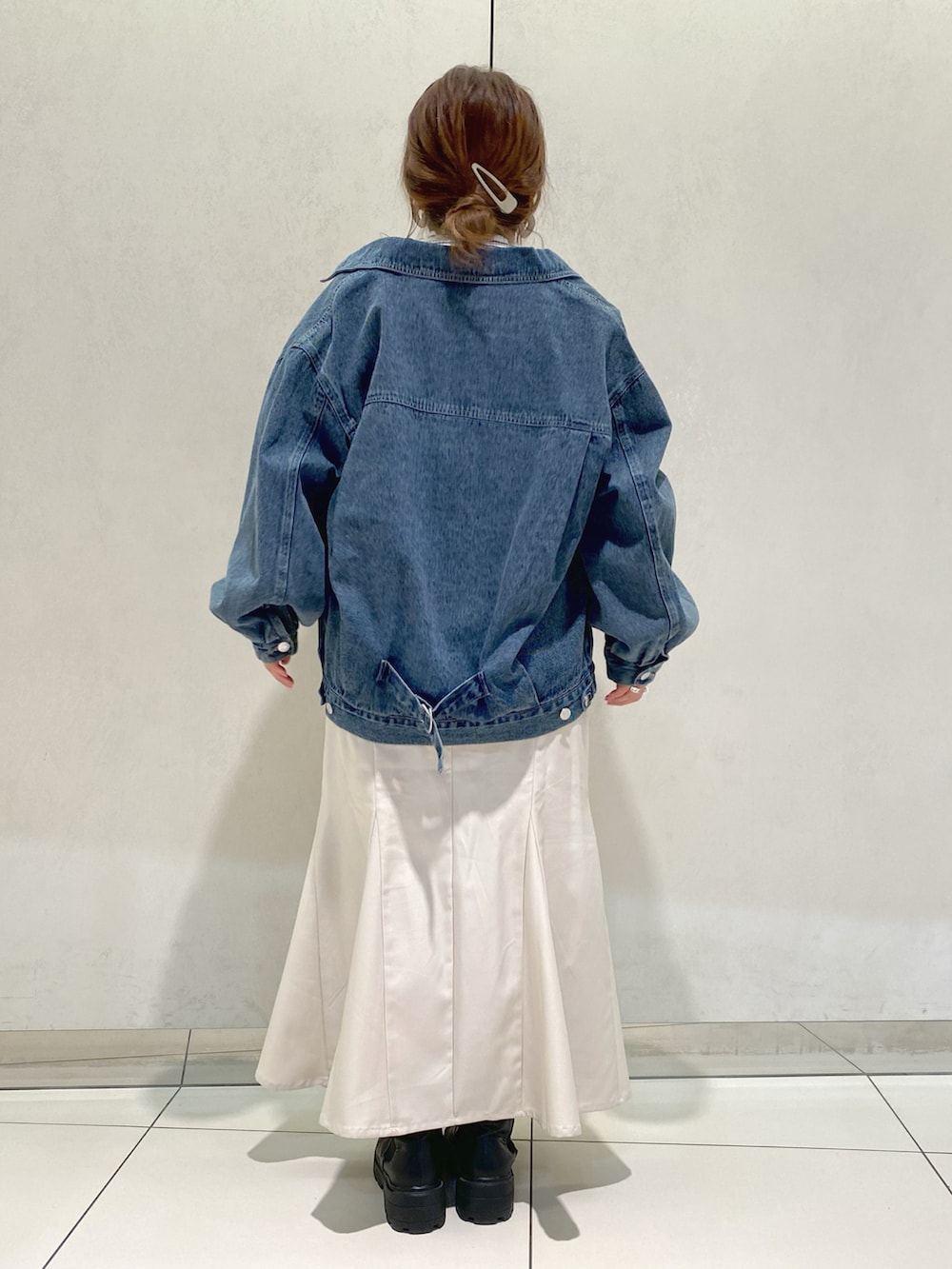 ブルー系のデニムジャケット、グレー系のカーディガン/ボレロ、ホワイト系のスカートを着用したレディースの春コーディネートの3枚目の写真