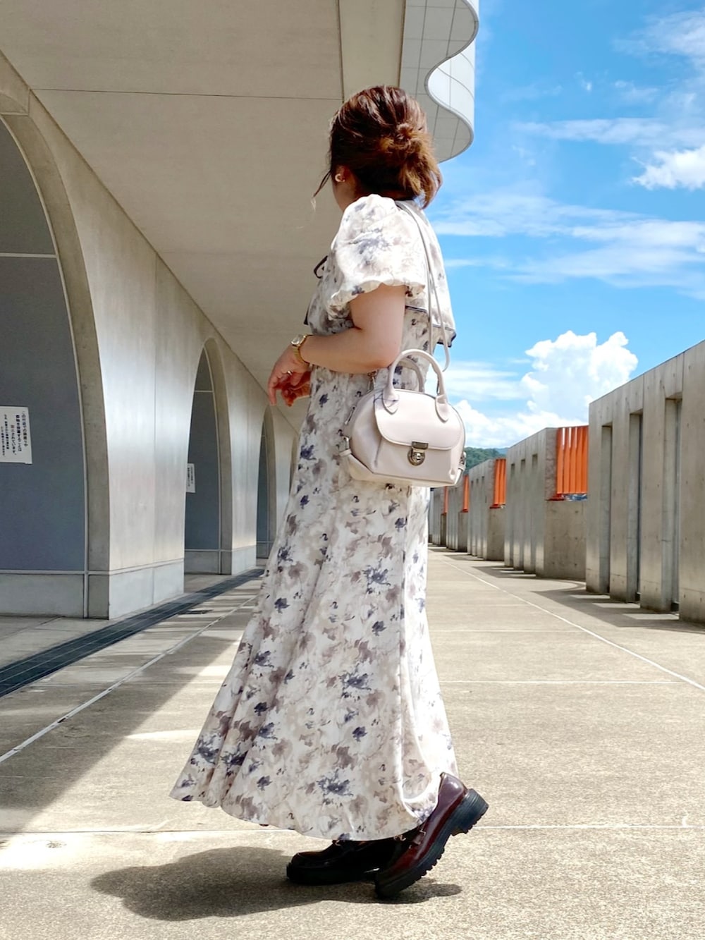 グレー系のワンピース、ホワイト系のショルダーバッグ、ブラウン系のローファーを着用したレディースの夏コーディネートの2枚目の写真