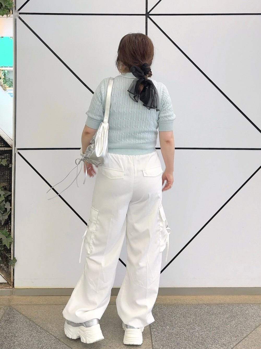 ブルー系のニット/セーター、ホワイト系のカーゴパンツ、シルバー系のショルダーバッグを着用したレディースの夏コーディネートの3枚目の写真