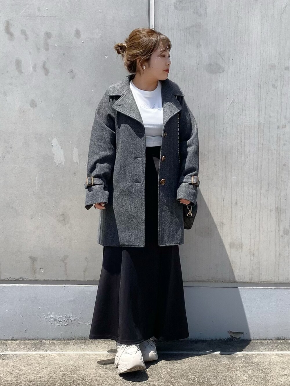 グレー系のステンカラーコート、ブラック系のショルダーバッグ、ブラック系のスカートを着用したレディースの夏コーディネートの2枚目の写真
