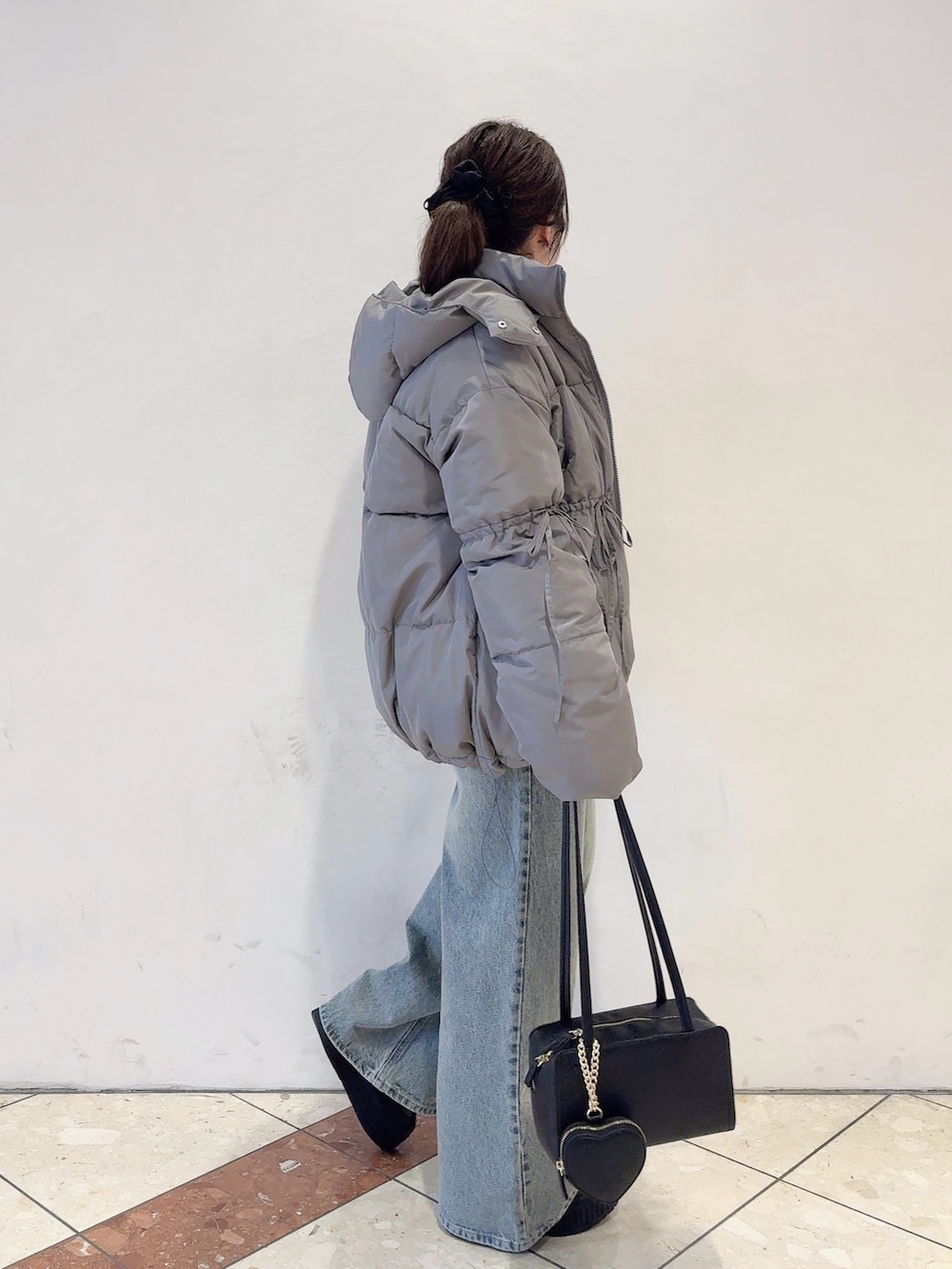 グレー系のダウンジャケット/コート、ホワイト系のニット/セーター、ブルー系のデニムパンツを着用したレディースの秋コーディネートの3枚目の写真